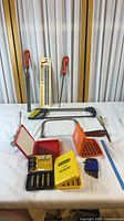 Overview of entire lot arranged on table showing files, saw frames, bit sets, hand tools