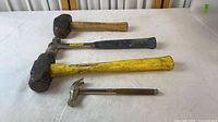 Four hammers laid out showing relative sizes and handles