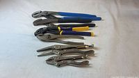 All six pliers arranged largest to smallest on white cloth