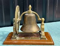 Front view of brass bell assembly on wood base