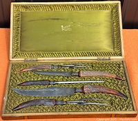 Closed walnut case open showing six carving implements fitted in green silk lining