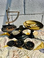 Full view of large cast iron balance scale with brass pan and three cast iron weights