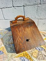 Front view showing slanted lid, knob and handle