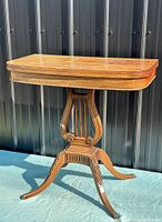 Full view of maple swivel-top card table against backdrop