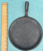 top view of round cast iron griddle next to ruler