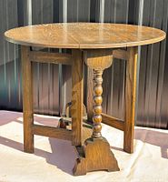 Perspective view of entire round oak folding table showing spindle legs and barley twist stretcher