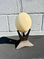 Full view of ostrich eggshell resting on cast iron Art Deco stand