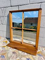Front view of wood framed four-pane mirror with bottom ledge