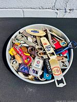 Top view of tray filled with assorted bottle openers showing quantity and variety