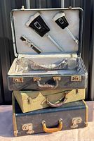 Stack of three suitcases, top one open showing grooming set