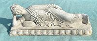 Full view of stone reclining Buddha sculpture on base