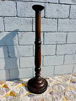 Full view of wood pedestal candle stand against wall