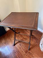 Table standing, full view showing leather top and folding legs