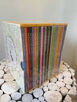 Side view showing multicolour spines of all 23 books inside sealed slipcase