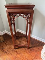 Full view of rosewood display table showing top, apron, legs and floor stretchers