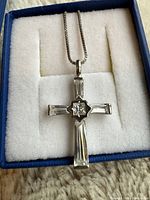 Front view of sterling silver cubic zirconia cross pendant on chain in box