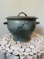 Front view of lidded stoneware pot on wood surface