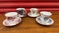 Four of the five teacup and saucer sets, assorted floral patterns