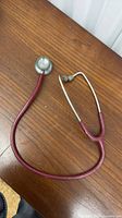 Entire stethoscope showing tubing, chestpiece, binaurals and eartips on wood surface