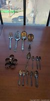 Full lot laid out: serving pieces, spoons, napkin rings