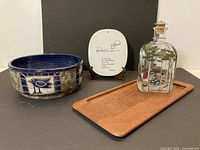 Group view of four Scandinavian collectible items: decanter, ceramic bowl, plate on stand, teak tray