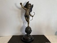 Full view of bronze cherub statue on marble base