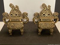 Front view of both brass incense burners showing lids, handles, feet