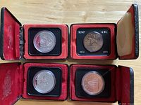 Four commemorative dollar coins in open red presentation boxes