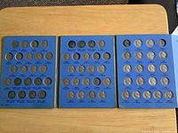 Three blue Whitman coin album panels opened with Jefferson nickels, nine empty slots