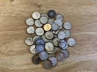 Pile of 1967 Canadian quarters on wood surface
