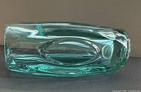 Side view of teal glass vase lying on side showing oval panel detailing