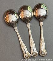 Three soup spoons showing shell motif handles