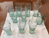 Front view of all 10 Coca-Cola green glasses on cloth