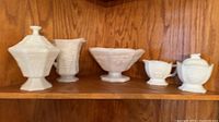 Five milk glass pieces displayed on wooden shelf