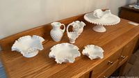 All seven milk glass pieces on wooden sideboard, showing relative sizes