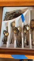 Drawer tray with stacks of small spoons, butter knives and pickle fork