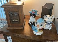 Front view of wooden PO box bank and three ceramic piggy banks
