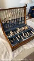 Open wood chest showing full flatware set