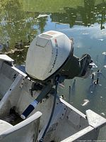 Johnson tiller outboard motor mounted on boat transom, showing cowling, tiller handle and propeller