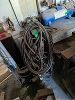 Coiled heavy welding cables resting on bench with attached hardware visible