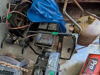 Full view of engine on tubular frame with attached components and surrounding items