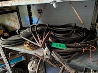 Coiled black welding leads with clamps and stinger on shelf
