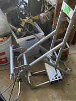 Overall view of silver steel tube mini bike frame lying on floor with missing components