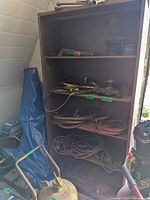 Full view of steel cabinet with shelves holding hoses, wires, parts