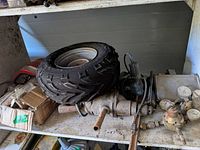 Shelf with mounted tire, corded tool, light, exhaust pipe and boxed hardware visible