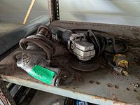 Angle grinder and drill resting on metal shelf showing overall wear