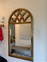 Full view of arched gold wall mirror hanging on wall