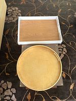 Round gold tray stacked over rectangular white/wood tray