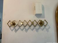 Front view of gold diamond pattern coat rack mounted on wall