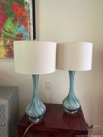 Two matching blown glass lamps on table showing full form with shades